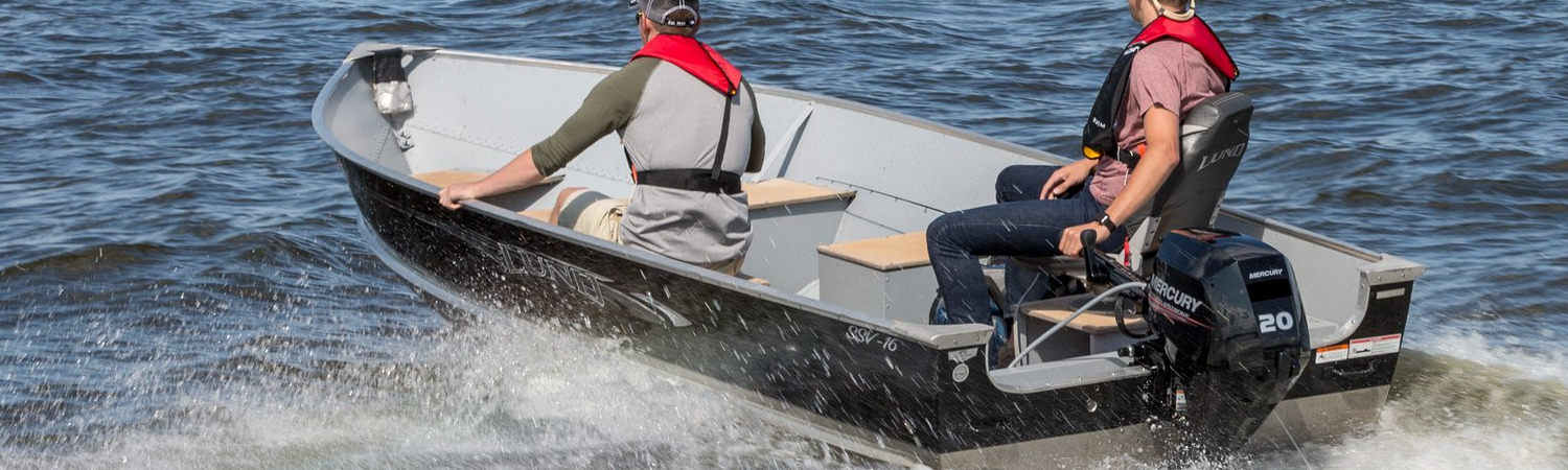 Two men motoring through a body of water in a boat.